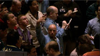 A group of businessmen gathered on a stockroom floor, looking up